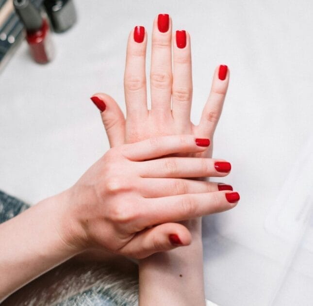 Two hands with bright red nails.